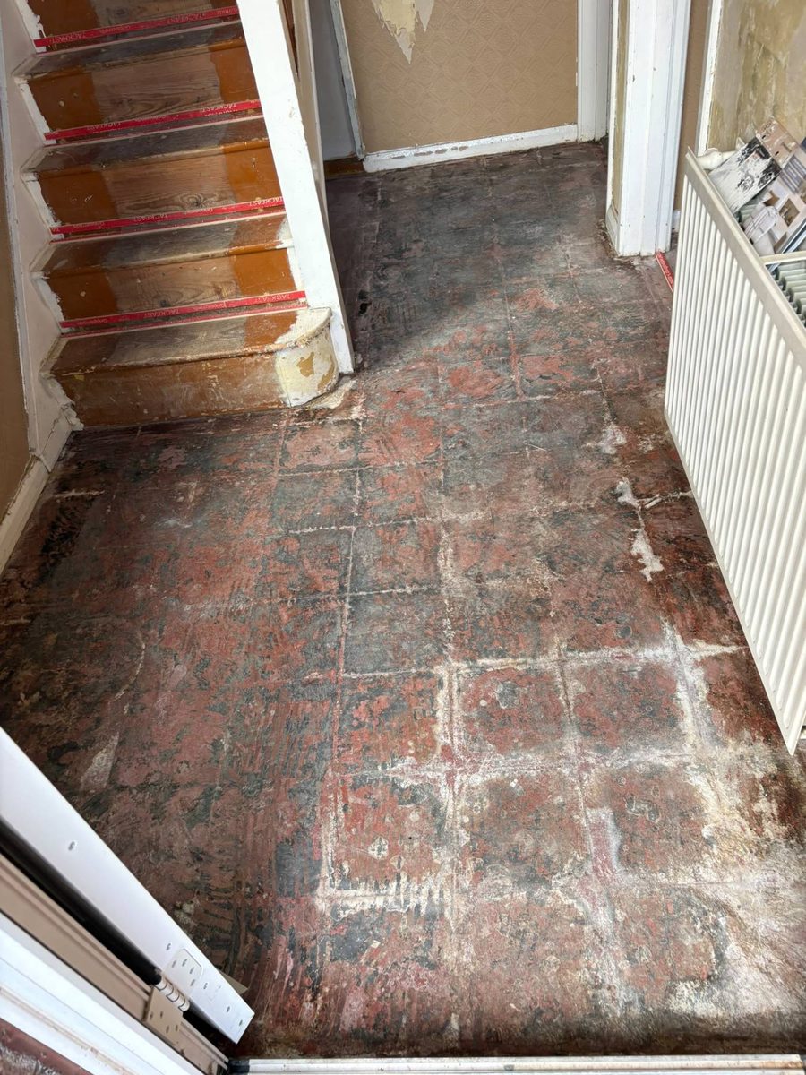 An old tiled hallway floor stripped back and uneven, before levelling